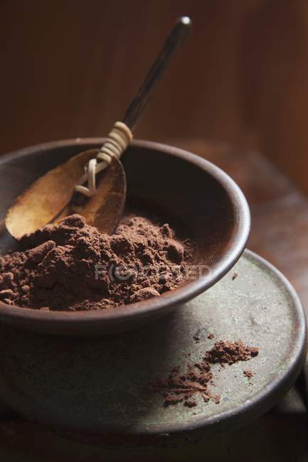 Closeup view of cocoa powder in a brown bowl with wooden spoon — Stock Photo