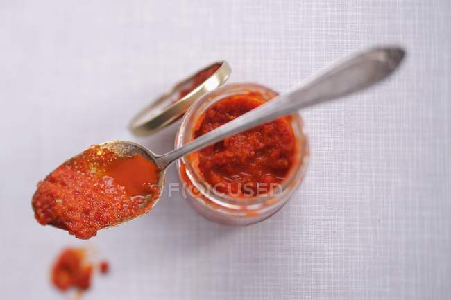 Closeup top view of Ajvar in a jar and on a spoon — Stock Photo