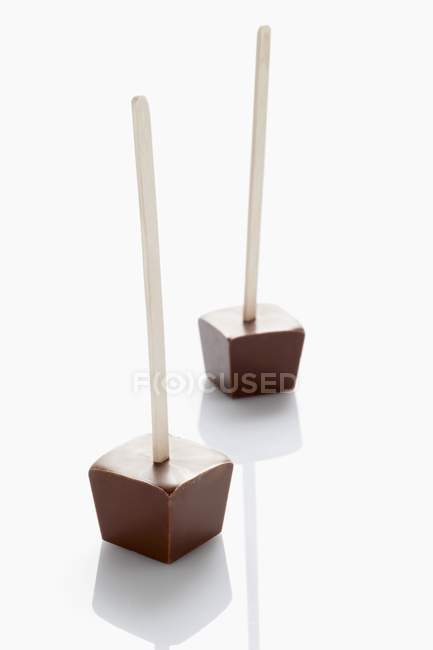 Cubos de chocolate en palos de madera - foto de stock