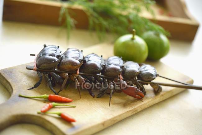 Espetos de lagostim, pimentões, limas e endro na mesa de madeira — Fotografia de Stock