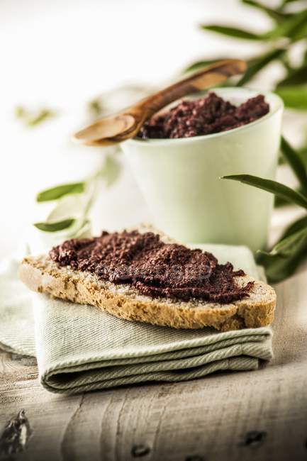 Crostino con crema di olive tostato con olive stese su telo su superficie tessile — Foto stock