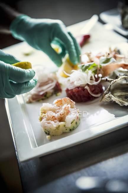 A chef arranging a fish dish on a white porcelain plate — Stock Photo