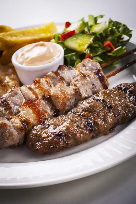 Mixed kebabs with salad and sauce — Stock Photo