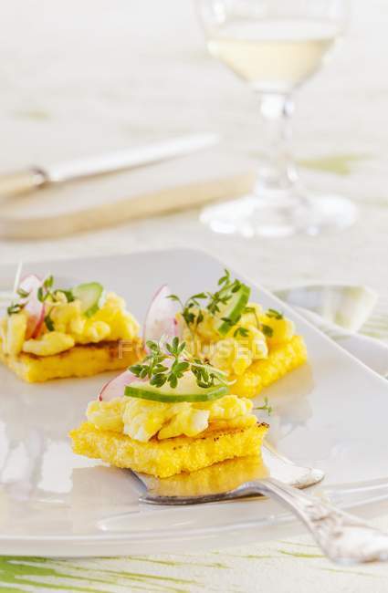 Polenta-Quadrate mit Ei, Gurke, Radieschen und Kresse auf Teller — Stockfoto