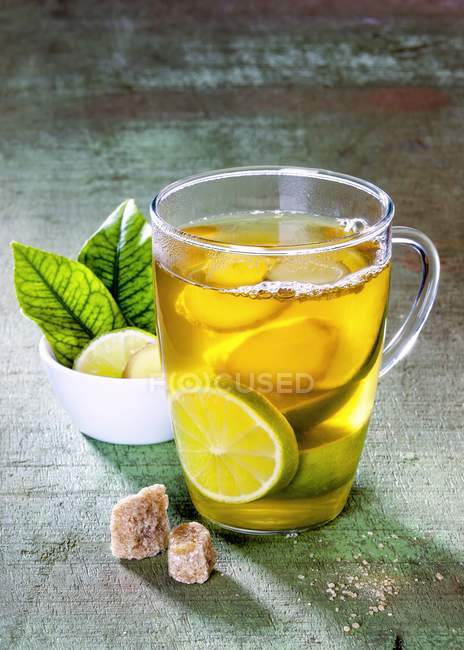 Ginger tea with limes in glass cup — Stock Photo