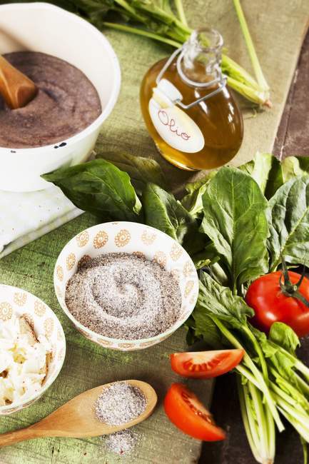 Buckwheat polenta with ingredients on table with towel and pots — Stock Photo