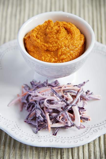 Красный перец и картофельное пюре с фиолетовым салатом в миске и на тарелке — стоковое фото