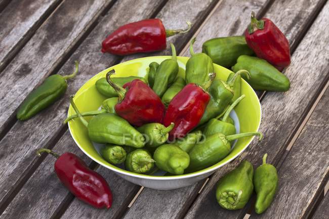 Red and green Pimientos de Padr on white plate on wooden surface — Stock Photo