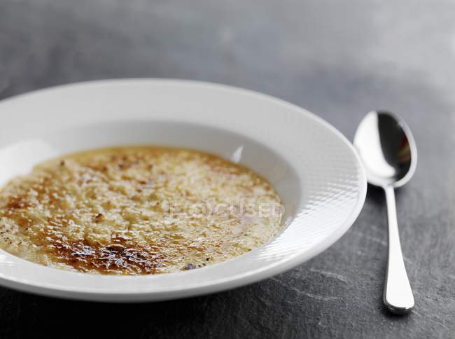 Closeup view of porridge with Demerara sugar in white bowl with spoon — Stock Photo