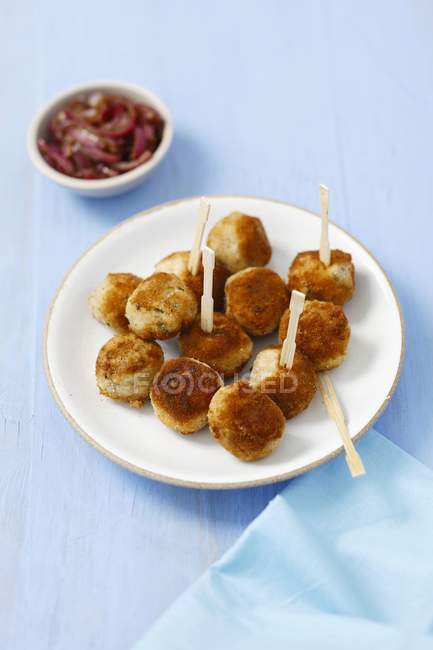 Croquetas de patata con caballa ahumada en plato blanco sobre superficie azul - foto de stock