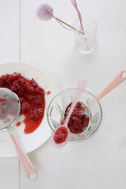 Top view of raspberries with a sieves and a plastic spoon — Stock Photo