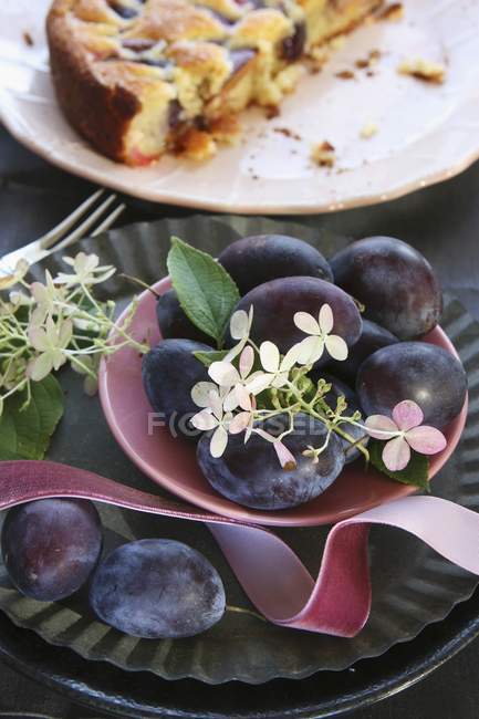 Bowl of plums with flowers — Stock Photo