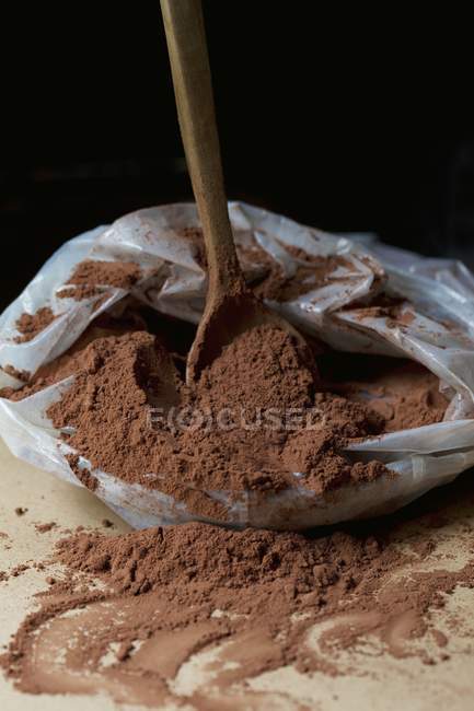 Вид крупним планом дерев'яна ложка в поліетиленовому пакеті какао-порошку — стокове фото