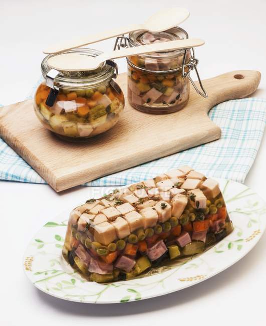 Truthahn-Aspik mit Gemüse und Erbsen auf weißer Oberfläche und Schneidebrett über Tisch — Stockfoto