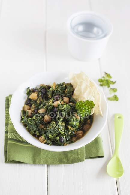 Zuppa vegetariana di spinaci e lenticchie su piatto bianco su asciugamano — Foto stock