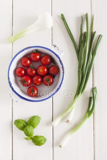 Ingredients for tomato sauce on white plate  over wooden surface — Stock Photo