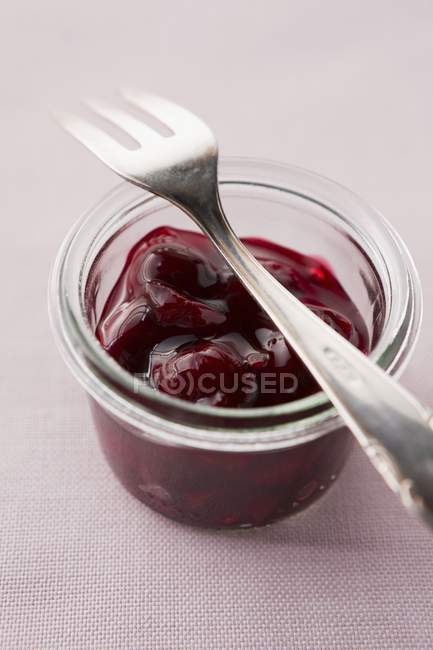 Mermelada de cereza en vaso con tenedor - foto de stock