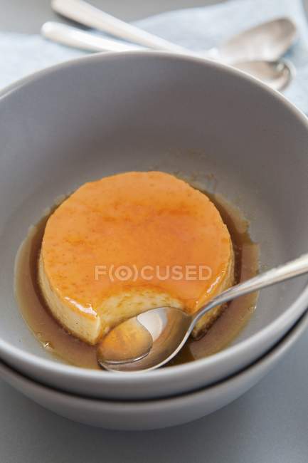 Closeup view of Creme caramel in bowl with spoon — Stock Photo