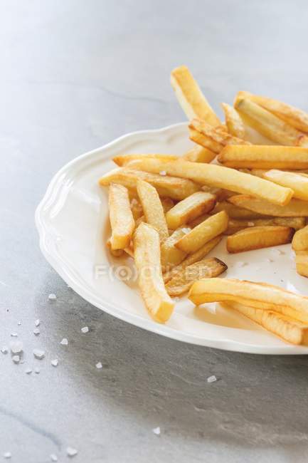 Chips em uma placa branca com sal marinho na placa branca — Fotografia de Stock
