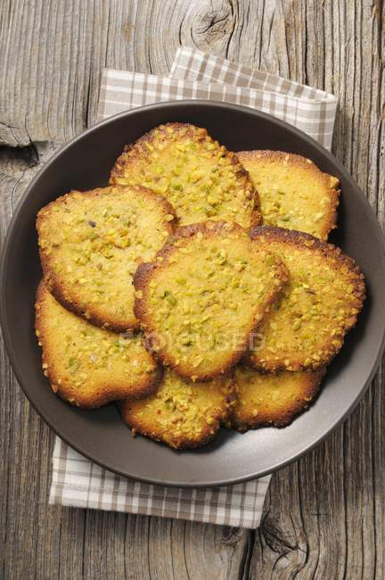 Top view of Tuiles with chopped pistachios on plate — Stock Photo