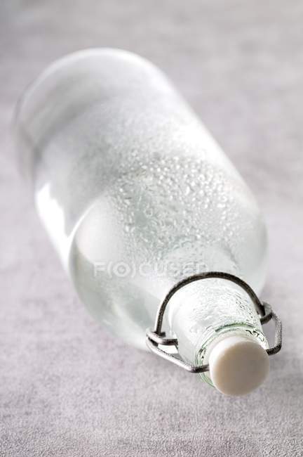Nahaufnahme einer nassen Wasserflasche auf der Seite — Stockfoto