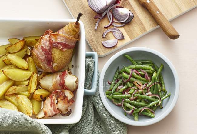 Bacon-wrapped pears with roast potatoes — Stock Photo