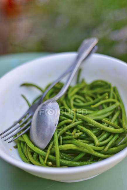 A green bean medley on white plate with fork and spoon — Stock Photo