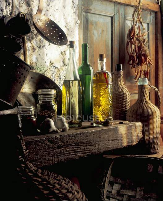 Botellas de aceites, ollas de cobre, jarras y especias en una cocina rústica - foto de stock
