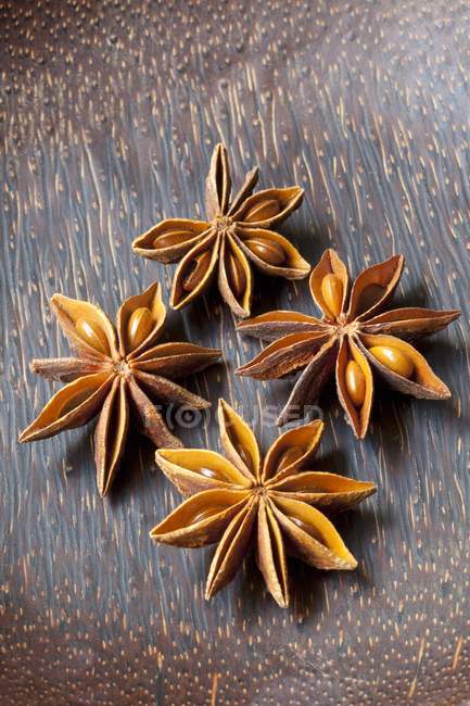 Vista close-up de quatro estrelas de anis na superfície de madeira — Fotografia de Stock