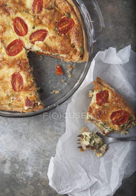 Tomato quiche with herbs over grey surface — Stock Photo