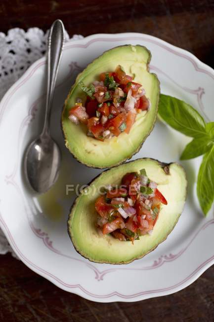 Abacate recheado com salsa de tomate em prato branco com colher — Fotografia de Stock