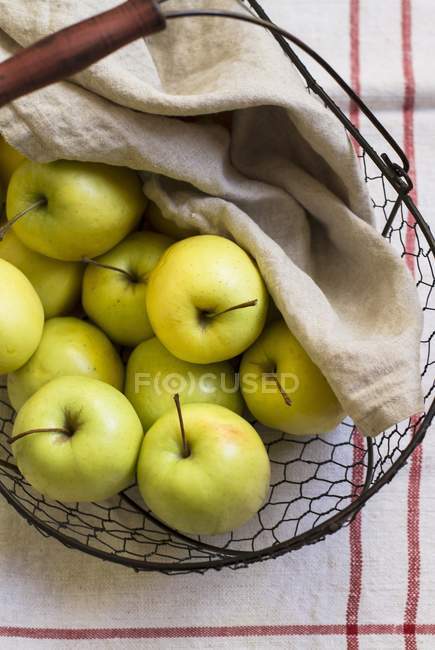 Green apples in wire basket — Stock Photo