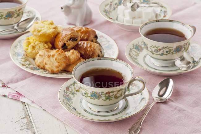 Vista de primer plano del té con pasteles dulces y cubos de azúcar - foto de stock