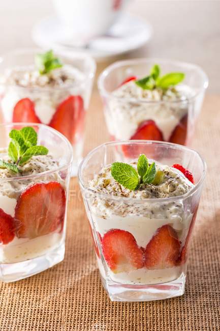 Vue rapprochée des fraises avec crème fouettée et feuilles de menthe — Photo de stock