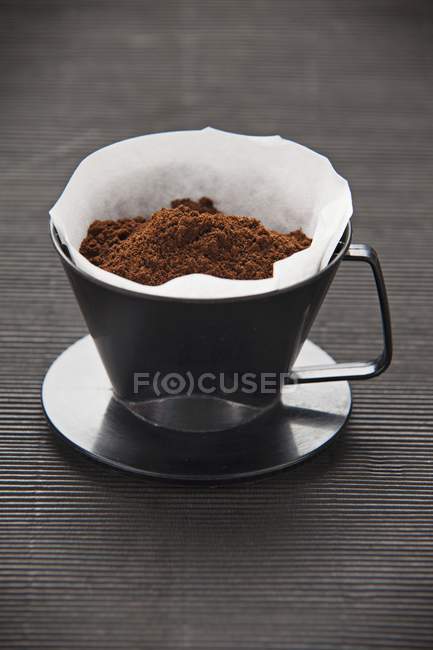 Vue rapprochée d'une tasse en plastique avec un papier filtre et de la poudre de café — Photo de stock