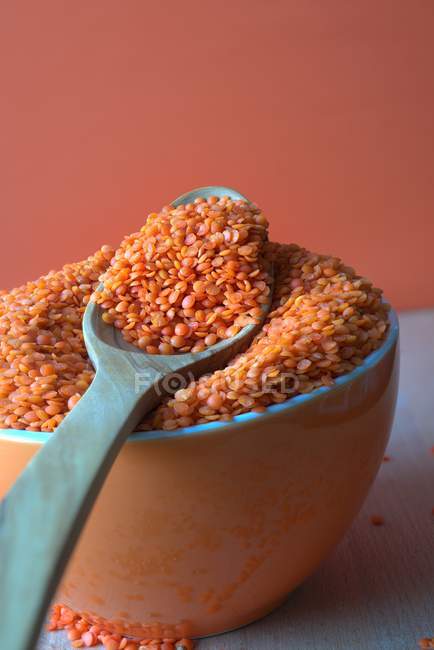 Closeup view of red lentils in a bowl with a wooden spoon — Stock Photo