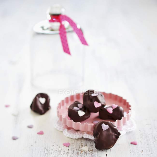 Plums in chocolate decorated with sugar hearts — Stock Photo