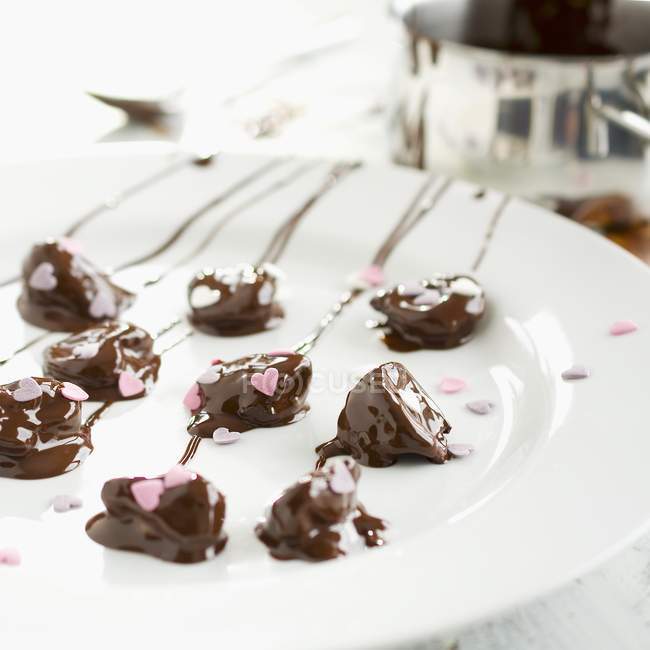 Chocolate-covered plums on plate — Stock Photo