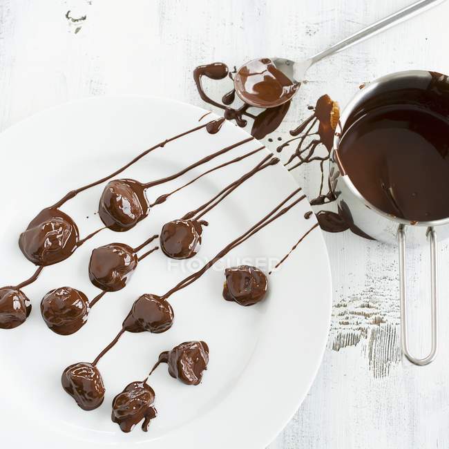 Ciruelas cubiertas de chocolate en el plato — Stock Photo