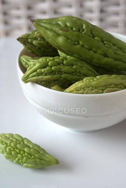 A bowl of bitter gourds over white surface — Stock Photo