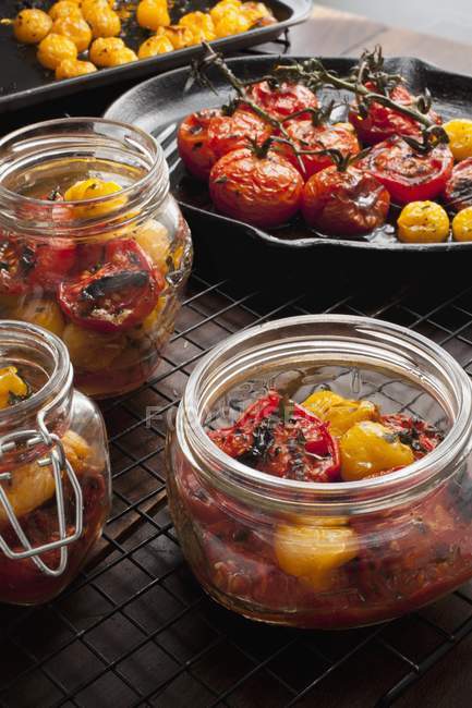 Tomates vermelhos e amarelos assados em jarros e frigideira — Fotografia de Stock