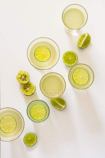 Vue du dessus du gin avec des citrons verts dans des lunettes — Photo de stock