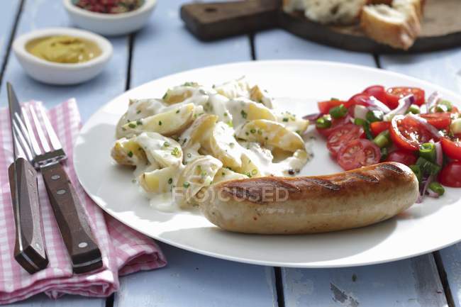 Salchichas con ensaladas de patata y tomate - foto de stock