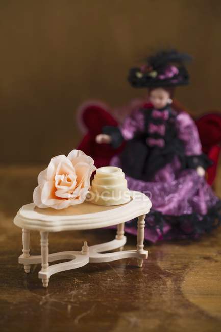 Vista de primer plano de praliné en una pequeña mesa con flores y muñecas - foto de stock