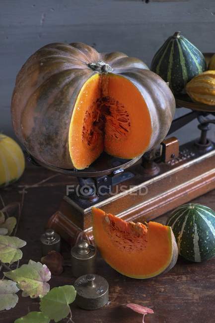 Zucche su un tavolo di legno con un vecchio paio di bilance da cucina — Foto stock