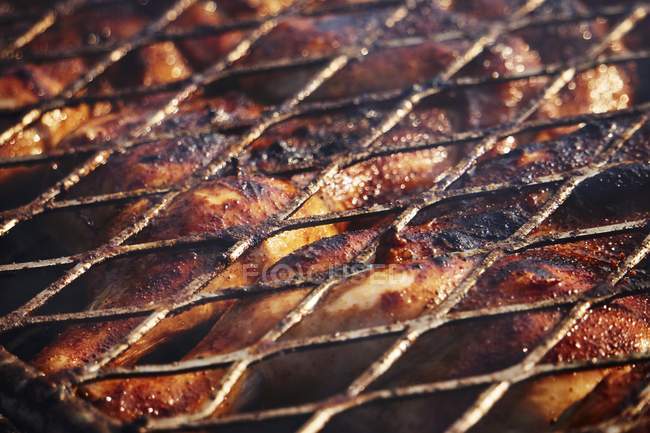 Closeup view of chicken roasting at barbecue rack — Stock Photo