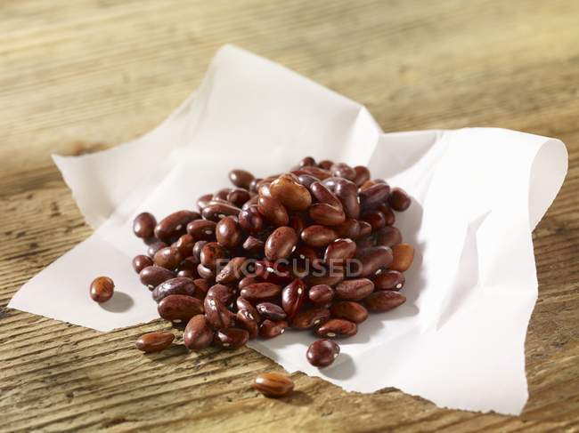 Borlotti beans on a piece of paper  over wooden surface — Stock Photo