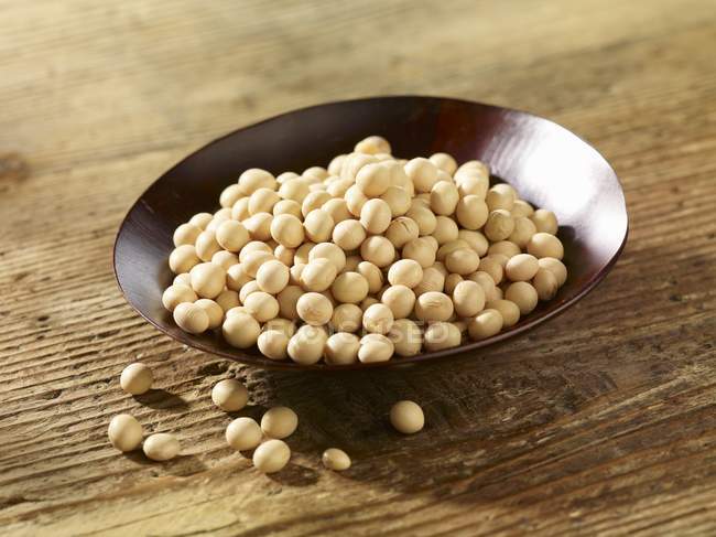 Soy beans in a dish on wooden surface — Stock Photo