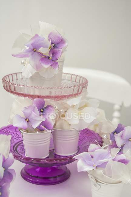Белые и фиолетовые гортензии цветы в белых металлических контейнерах на стенде стеклянного торта — стоковое фото