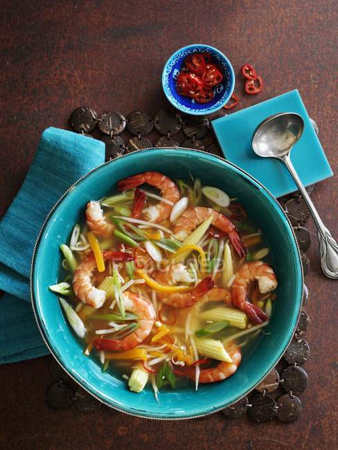 Spicy vegetable soup with prawns in green bowl over wooden surface — Stock Photo